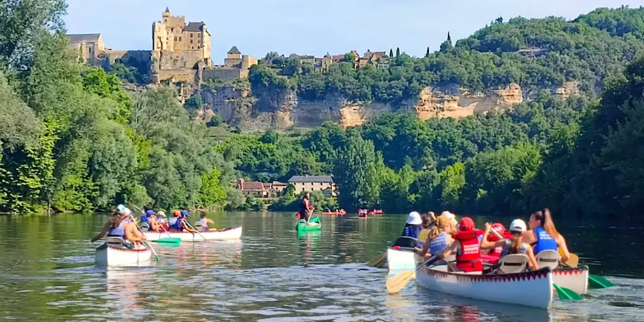 Des gens en canoë sur une rivière, avec un château en arrière-plan.