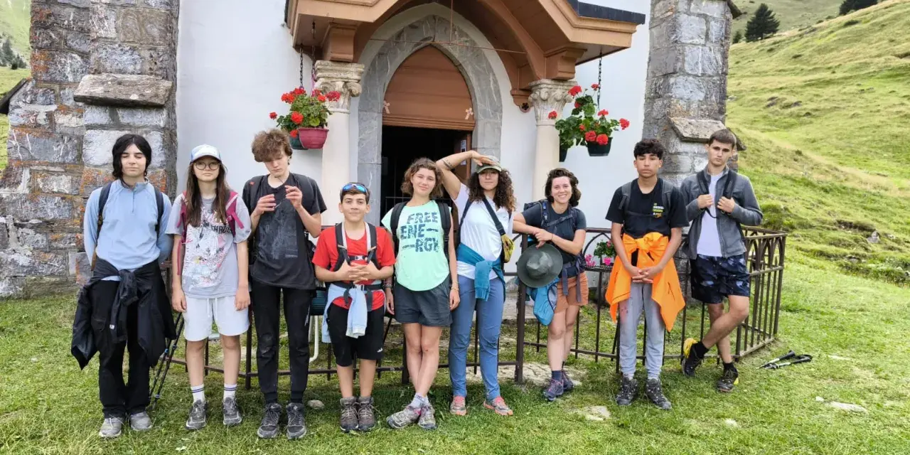 Groupe d'enfants en tenue de randonnée devant une petite église en montagne.