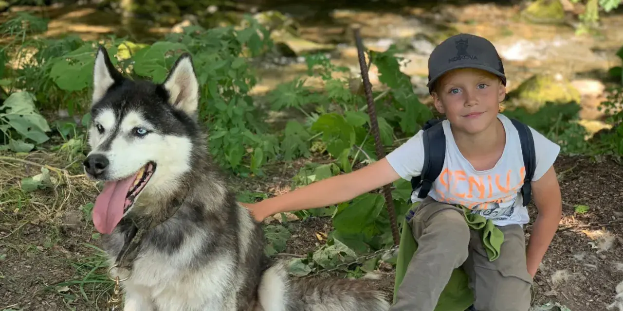 Un garçon et son husky profitent d'une aventure en pleine nature, un souvenir de leur colonie de vacances à l'étranger.