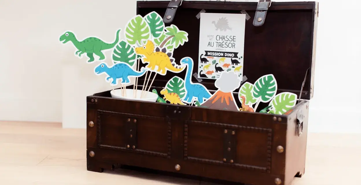Coffre en bois rempli de décorations de dinosaures et de feuilles tropicales.