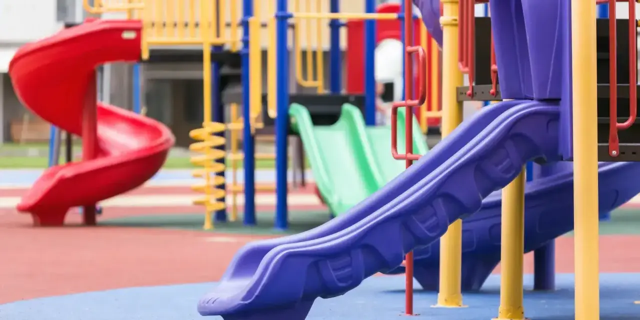 Aire de jeux colorée avec toboggans rouge, vert et violet.