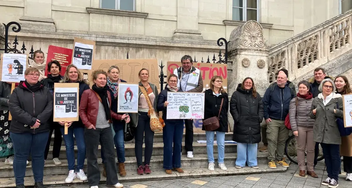 Un groupe de personnes manifeste devant un bâtiment, tenant des pancartes "Le Ministère de l'injustice".
