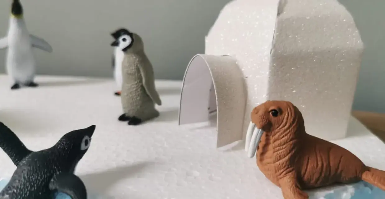 Maquette d'igloo blanc scintillant avec des figurines de phoques et de morses sur un décor de glace.