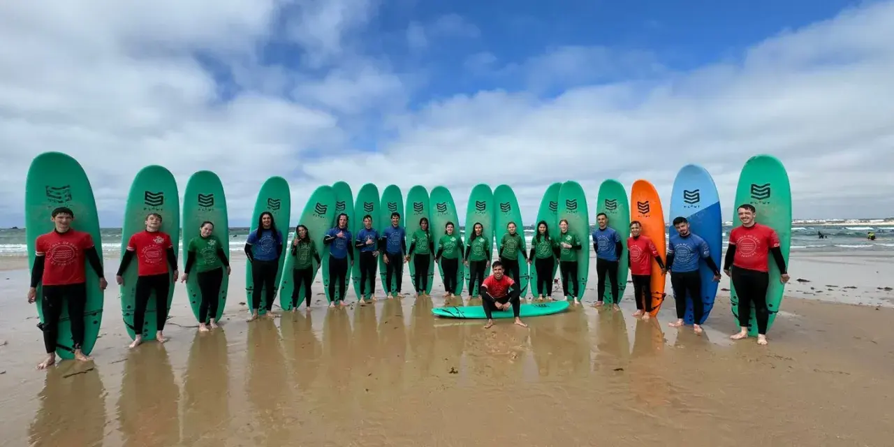 Groupe de jeunes souriants avec des planches de surf sur une plage.