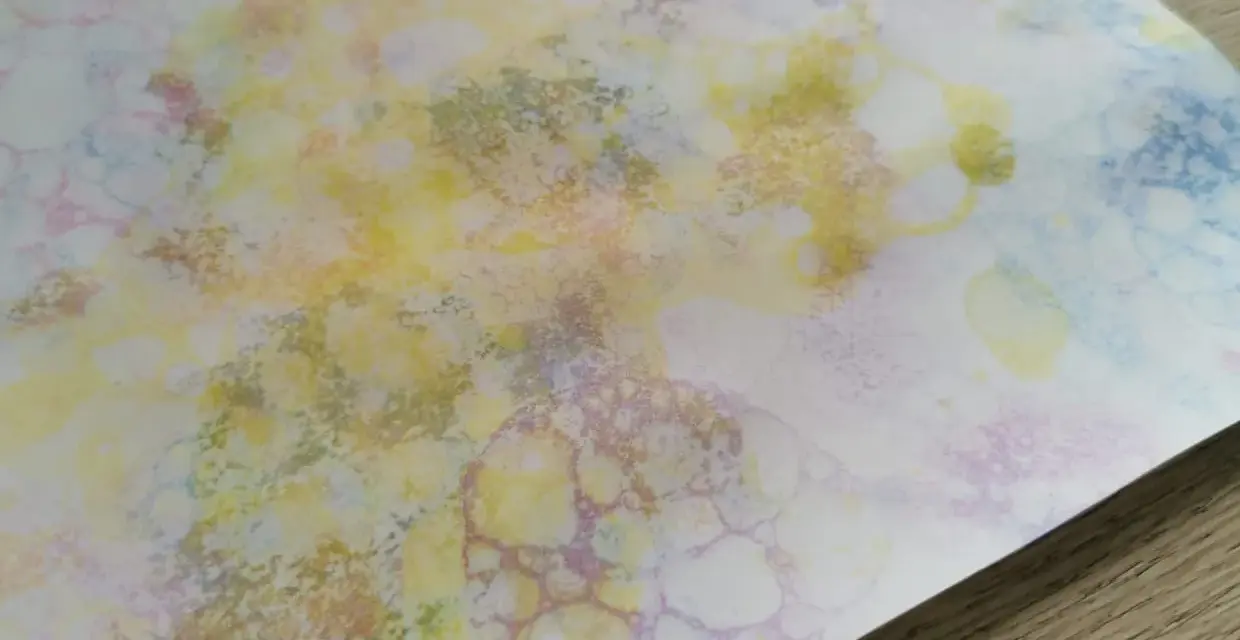 Peinture à bulles colorée sur papier blanc, avec des formes rondes et des éclaboussures.
