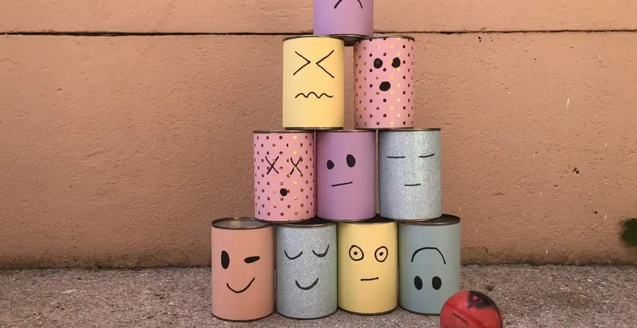 Pyramide de boîtes décorées de visages pour une kermesse chamboule tout. Un dessin amusant prêt à être renversé !