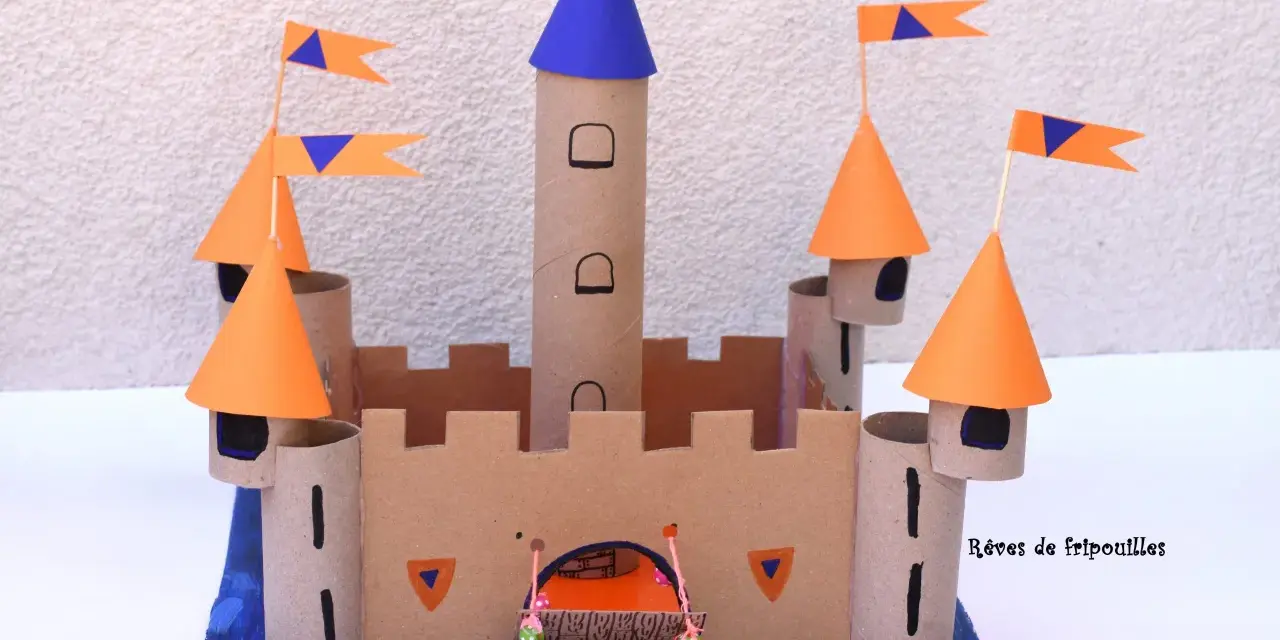 Château fort en carton avec tours, drapeaux orange et bleus, et une herse.