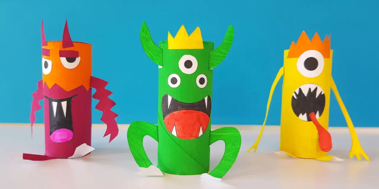 Trois monstres colorés faits à la main, en rouleaux de papier toilette, sur fond bleu.