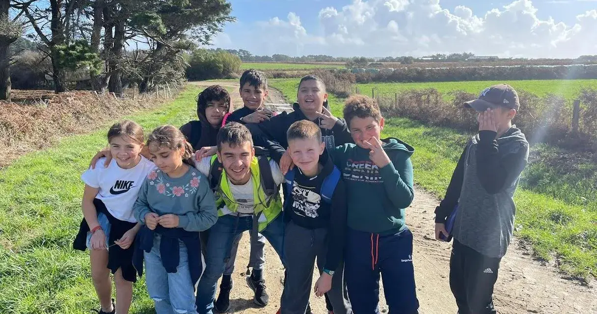 Groupe d'enfants souriants sur un chemin de terre, par une journée ensoleillée.