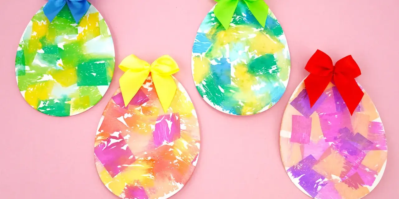 Quatre œufs décorés de papier crépon coloré et ornés de rubans sur fond rose.