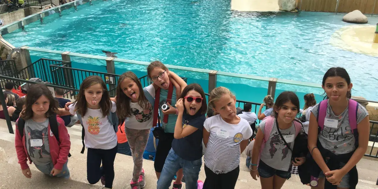 Des enfants en colonie de vacances en Île-de-France s'amusent devant un bassin de spectacle aquatique, faisant des grimaces.
