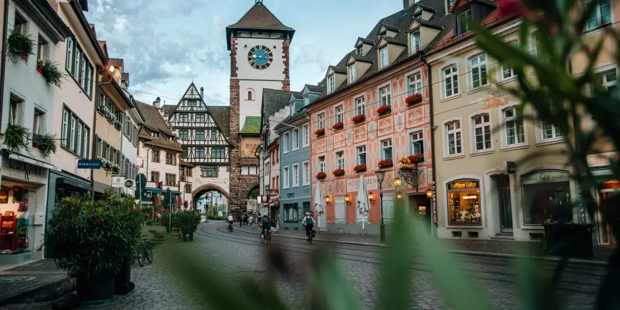 Vue d'une rue pavée à Fribourg-en-Brisgau avec une tour à horloge et des bâtiments colorés.