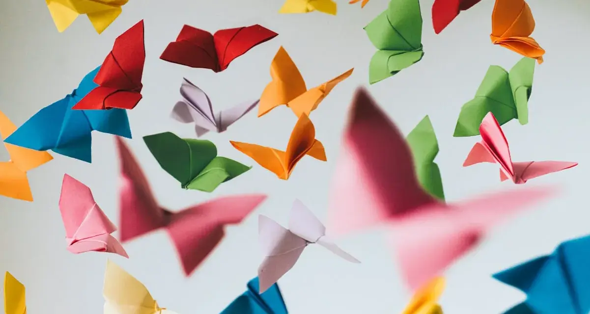 Papillons en origami multicolores flottant sur fond clair.