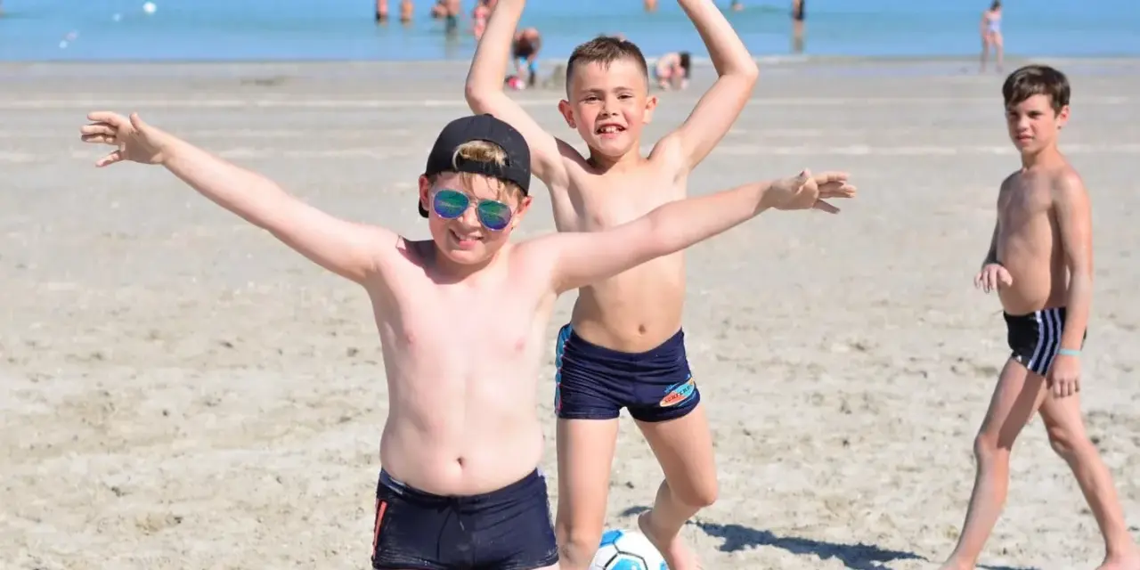 Enfants joyeux jouant au ballon sur une plage du colo sud de la France.