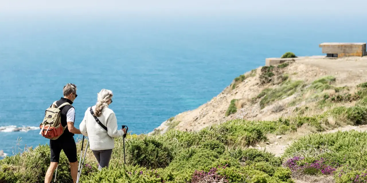 Couple randonnant sur les falaises de Jersey, profitant d'un séjour linguistique et d'une vue imprenable sur la mer.