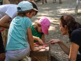 Une famille résout une énigme pour course d'orientation, manipulant des jetons sur un jeu en bois.