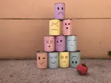 Pyramide de boîtes décorées de visages pour une kermesse chamboule tout. Un dessin amusant prêt à être renversé !