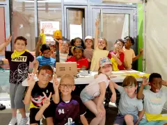 Des enfants joyeux, certains avec des maquillages amusants, profitent d'une activité lors d'un accueil de loisirs.