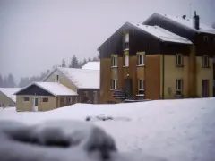 Bâtiments enneigés dans une colonie des Vosges, sous un ciel gris.