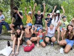 Des jeunes joyeux font des signes de rock lors d'une colonie de vacances PACA. Ils profitent de la nature et de l'aventure.
