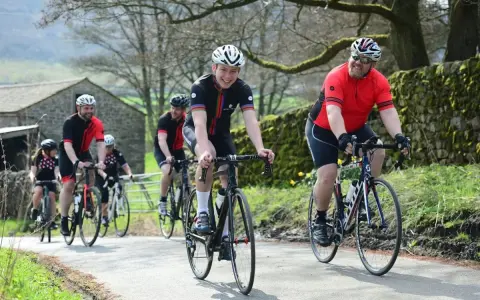 Un groupe de cyclistes souriants roule sur une route de campagne, respectant le code de la route pour cycliste en groupe.