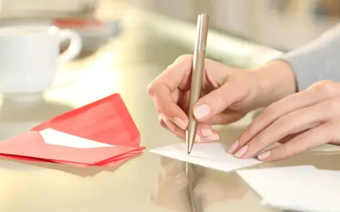 Main tenant rédige un modèle d'autorisation parentale TAM. Une tasse de café et une enveloppe rouge sont à proximité.