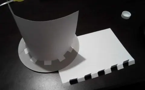 Chapeau en carton en cours de création, avec des pièces découpées et un patron.