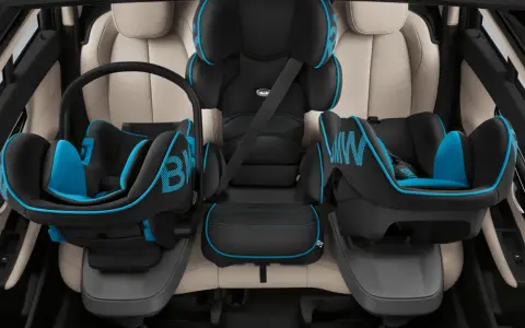 Trois sièges auto pour enfant, noir et bleu, installés sur des sièges en cuir clair. Le transport enfant en voiture est sécurisé.