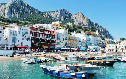Vue pittoresque de Capri, un joyau pour votre naples voyage. Bateaux colorés dans une eau turquoise, face aux maisons et aux falaises majestueuses.