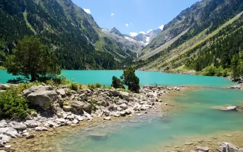 Un lac turquoise aux reflets émeraude, niché au cœur d'une vallée verdoyante des Pyrénées. Un paysage de carte postale, invitant à la contemplation.