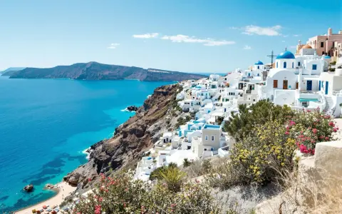 Vue panoramique de Santorin, Grèce, avec des maisons blanches et des dômes bleus surplombant la mer Égée.