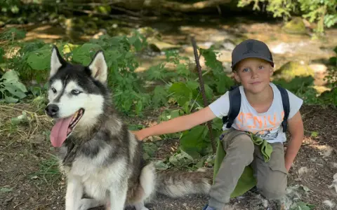 Un garçon et son husky profitent d'une aventure en pleine nature, un souvenir de leur colonie de vacances à l'étranger.