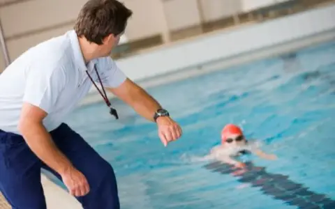 Entraîneur surveillant un nageur, peut-être pour un certificat de natation pour colonie.