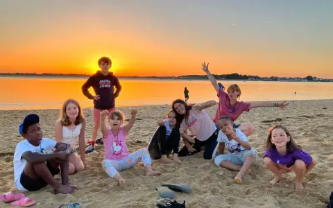 Groupe d'enfants joyeux sur une plage au coucher du soleil.