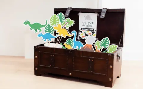 Coffre en bois rempli de décorations de dinosaures et de feuilles tropicales.