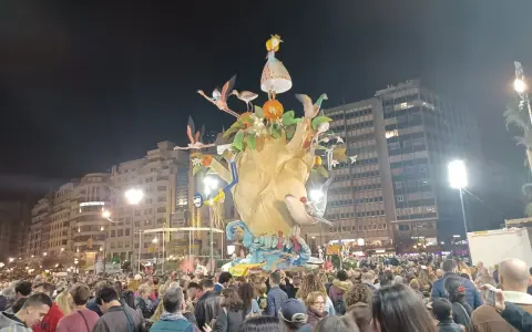 La foule admire une immense sculpture colorée, une scène typique du déroulement des Fallas de Valencia, avec des flamants roses et une petite fille perchée en haut.