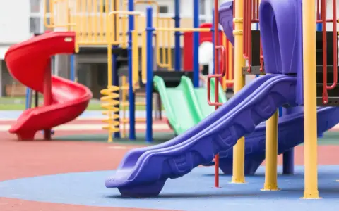 Aire de jeux colorée avec toboggans rouge, vert et violet.