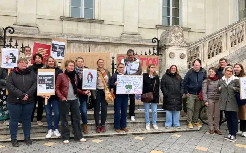 Un groupe de personnes manifeste devant un bâtiment, tenant des pancartes "Le Ministère de l'injustice".