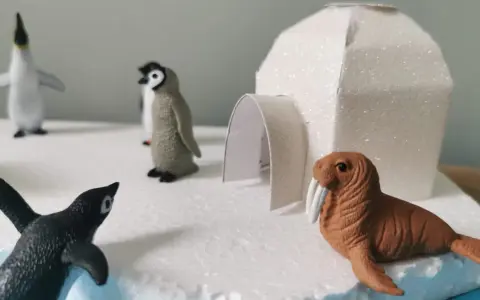 Maquette d'igloo blanc scintillant avec des figurines de phoques et de morses sur un décor de glace.