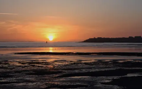 Coucher de soleil sur la mer à Saint-Pair-sur-Mer. La lumière dorée illumine le ciel et l'eau, invitant à la contemplation.