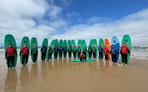 Groupe de jeunes souriants avec des planches de surf sur une plage.