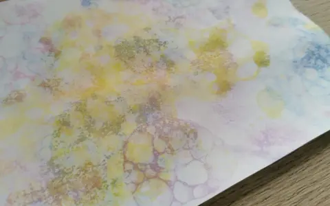 Peinture à bulles colorée sur papier blanc, avec des formes rondes et des éclaboussures.