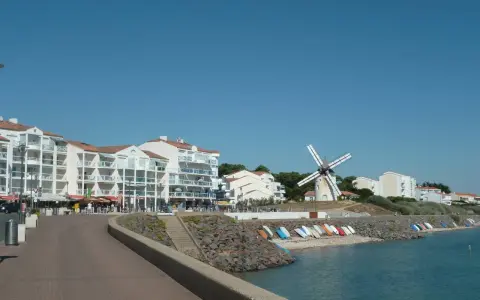 Vue de Jard-sur-Mer avec son port, ses immeubles blancs, son moulin et sa plage bordée de bateaux.