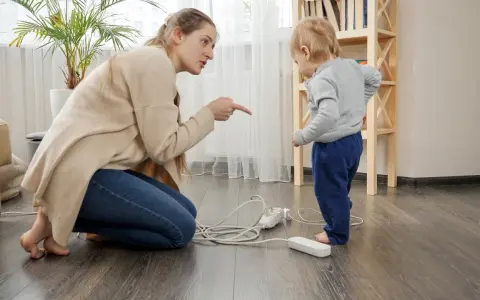 Une femme réprimande un enfant près de prises électriques au sol.