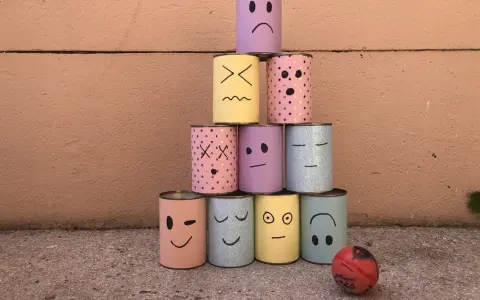 Pyramide de boîtes décorées de visages pour une kermesse chamboule tout. Un dessin amusant prêt à être renversé !