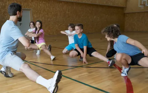 Un entraîneur guide des enfants lors d'une séance d'étirements. L'accueil des mineurs dans cette association sportive est une priorité.
