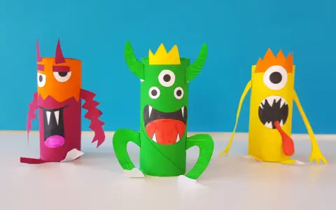 Trois monstres colorés faits à la main, en rouleaux de papier toilette, sur fond bleu.