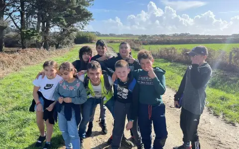 Groupe d'enfants souriants sur un chemin de terre, par une journée ensoleillée.