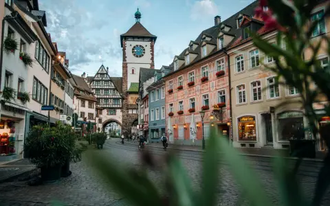 Vue d'une rue pavée à Fribourg-en-Brisgau avec une tour à horloge et des bâtiments colorés.
