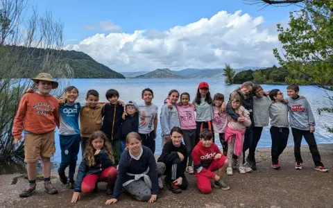 Un animateur pour combien de jeunes ? Un groupe d'enfants souriants pose devant un lac, prêts pour l'aventure.